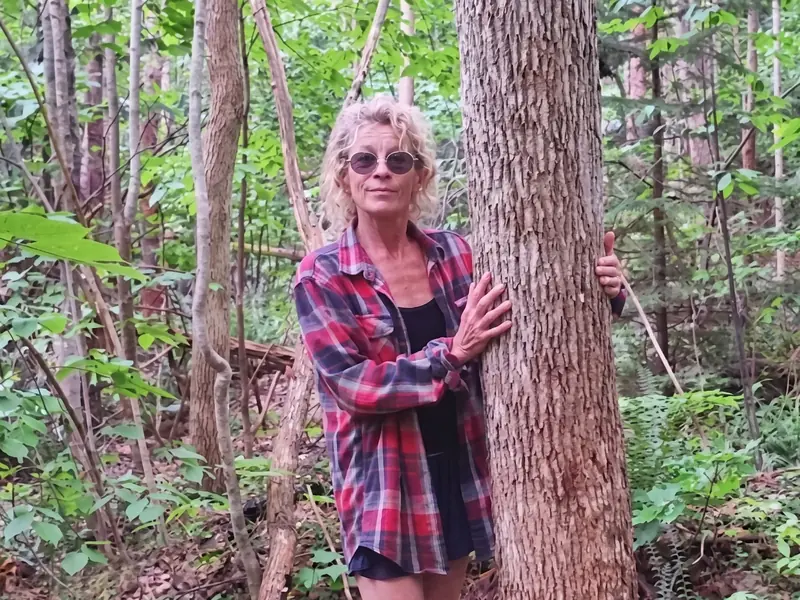 Becky Bryne beside an ironwood tree in woodland